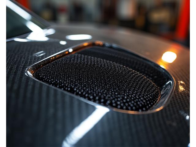 Artistic close-up of a meticulously crafted carbon fiber hood vent.